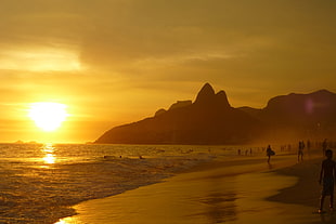 photo of people on seashore during sunset