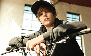 Justin Bieber wearing black jacket sitting on bike
