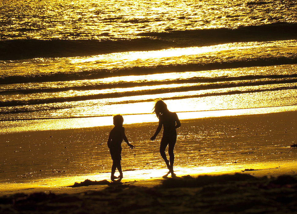 silhouette of two children playing near the seawave HD wallpaper