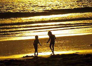 silhouette of two children playing near the seawave HD wallpaper