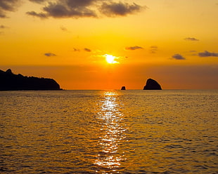 silhouette of island on body of water against sunlight HD wallpaper