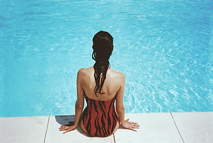 woman wearing black and orange monokini near swimming pool