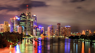 lightened city buildings near body of water at night time