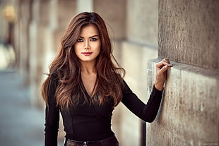 woman wearing black v-neck long-sleeved shirt beside wall during daytime HD wallpaper