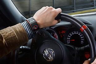 person in brown sleeved holding steering wheel