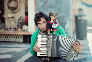 man wearing green shirt playing accordion with tan dog HD wallpaper