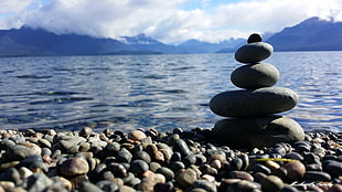 five pile of stones near sea under white clouds during daytime HD wallpaper