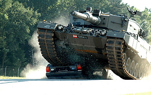 gray military tank wrecking the black car