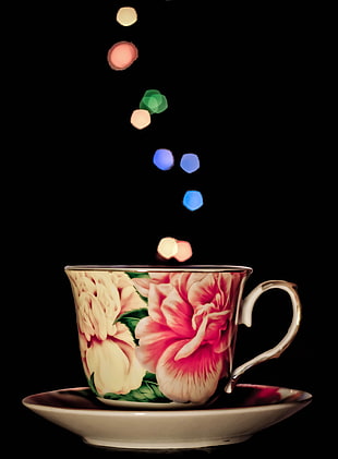 pink and white flowers printed teacup on a saucer with bokeh lights