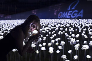 shallow focus photography of woman smelling white flower