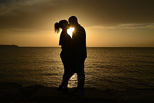 silhouette photo of couple kissing near body of water