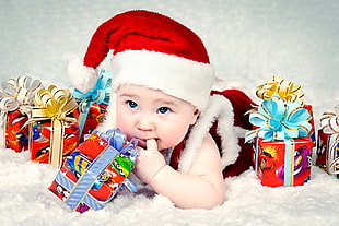 baby in santa hat surrounded by gift boxes