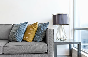 white table lamp base with black lamp shade besides gray leather sofa