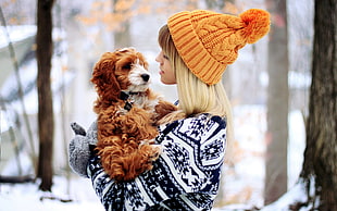 woman in sweater carrying brown dog