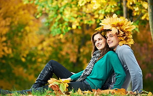 man and woman sitting covered with leaves
