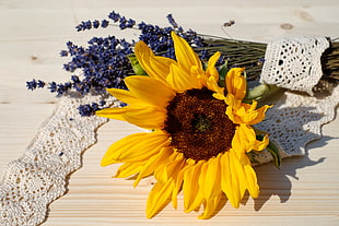 yellow sunflower near bouquet of lavender on brown surface