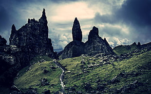 grey rock mountain near green grass field under white cloudy sky