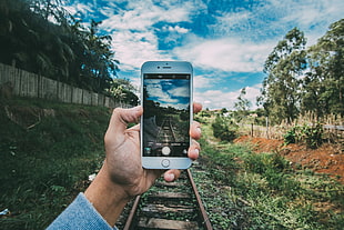 person taking photo of railroad at daytime