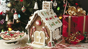 gingerbread house beside footed bowl and red gift box