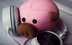 photo of pink pig plush toy beside white headphones