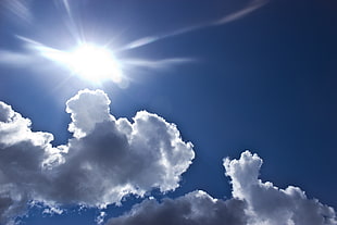 photo of ray of sun with nimbus clouds and clear blue calm sky