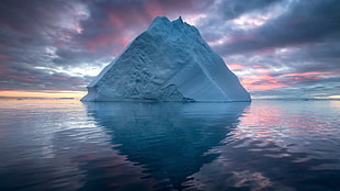 iceberg over calm body of water during golden hour
