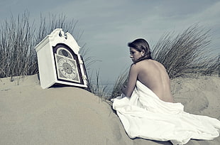 topless woman sitting on sand photogoraph