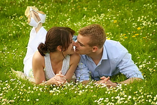 woman in white dress and man in blue dress shirt sitting in grass