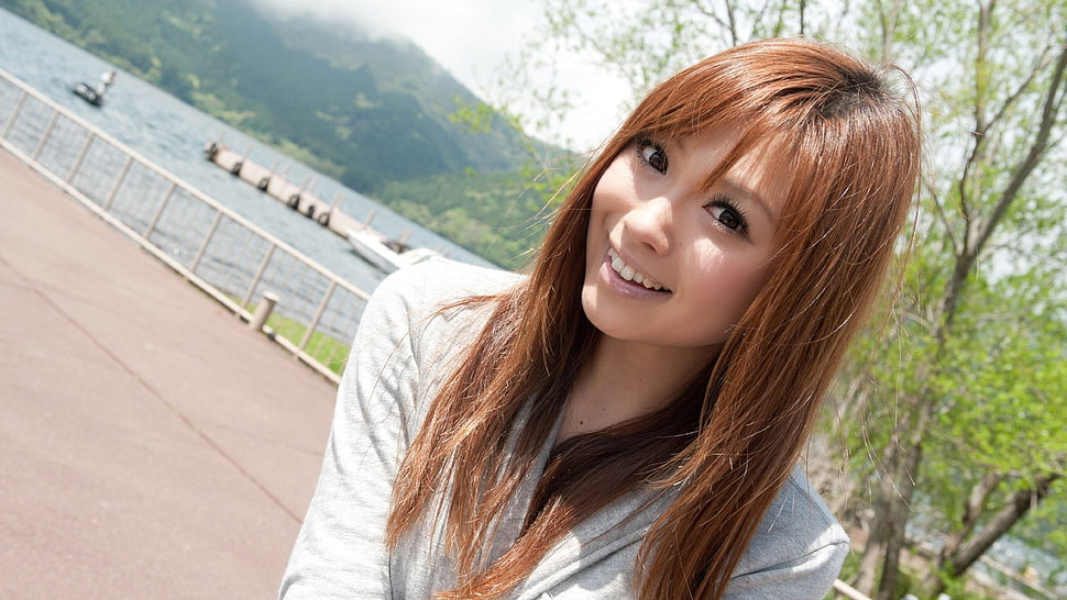 woman wearing white top smiling near body of water during daytime HD wallpaper