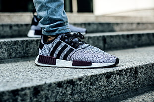person wearing gray-and-black Adidas NMD's