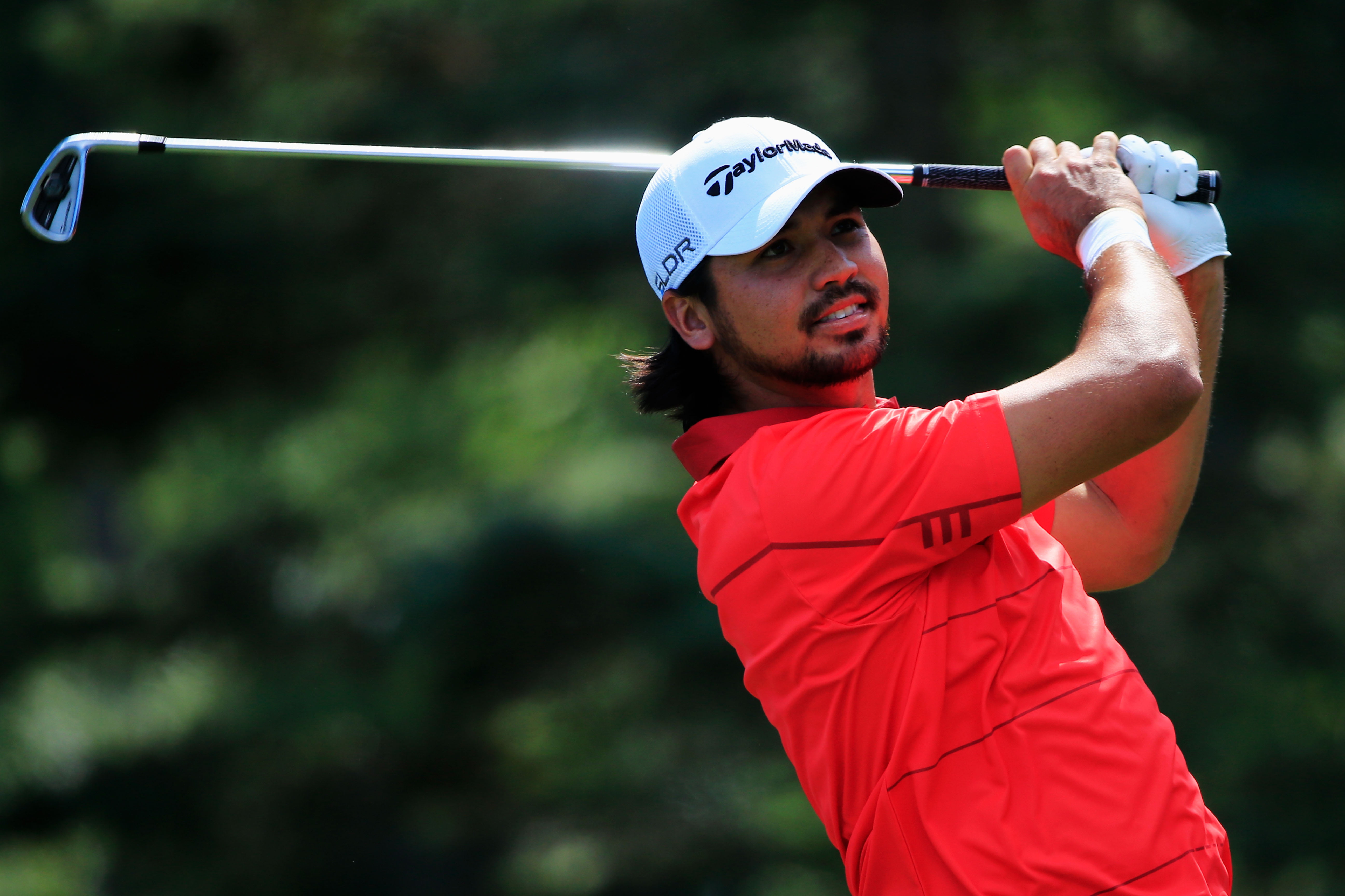 man in red polo shirt holding gray golf club