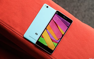 turned on white Xiaomi Redmi Android smartphone on orange textile