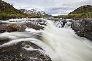 landscape photo of water falls surrounded by mountains