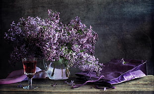 purple flowers with clear glass vase on table