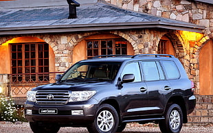 black Toyota Land Cruiser parked beside brown stone house