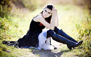shallow focus photography of woman wearing black dress sitting on green grassy field