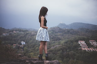 woman wearing black standing on stone cliff