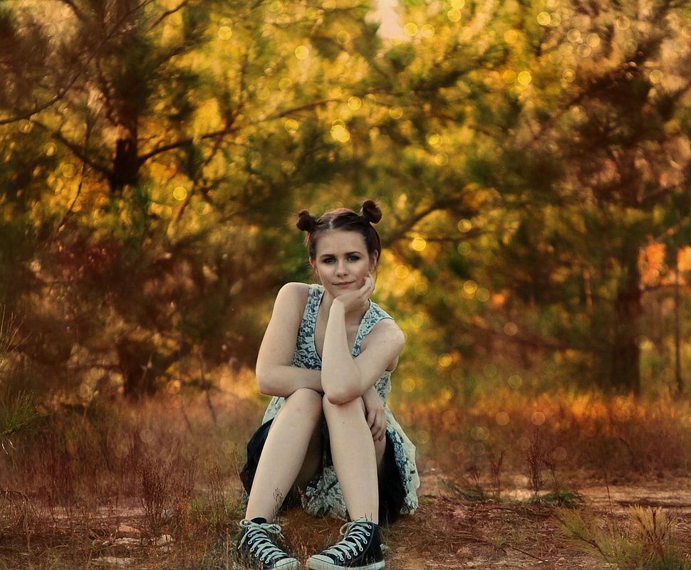 woman in white floral sleeveless shirt squatting on brown grasses near green trees during daytime HD wallpaper