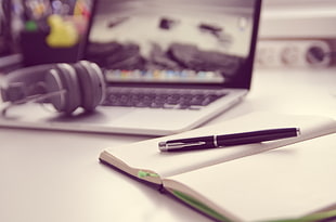 black ball point in white notebook on white wooden table beside MacBook Pro HD wallpaper