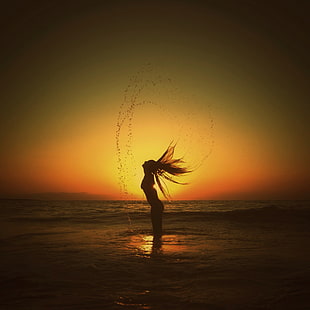 silhouette photography of  woman standing in body of water