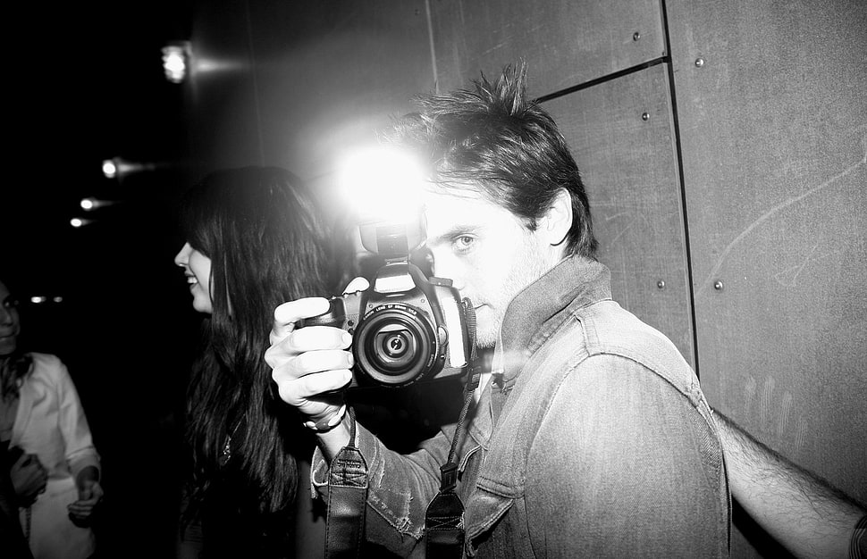 man in gray scale photo while holding black DSLR camera HD wallpaper