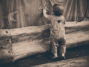 grayscale photo of toddler standing holding textile