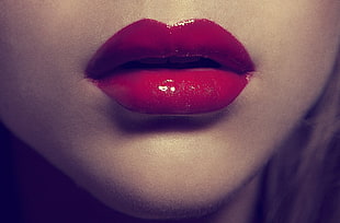 closeup photo of woman put red lipstick