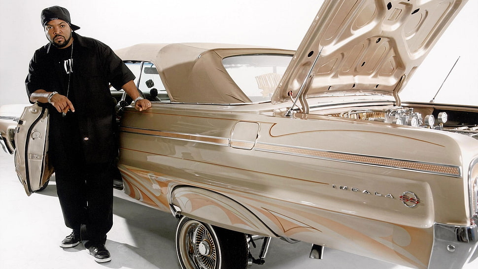man wearing black jacket and pants with cap lining on classic car HD wallpaper