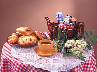 photo of baked bread on plate near cup with saucer on top of table