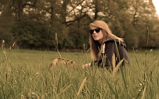 photo of woman wearing black pullover hoodie sitting on grass