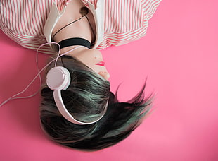 woman wearing corded headphone while lying down
