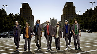 seven men wearing suit jacket near high-rise building