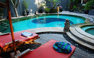 green and blue striped towel on top of red outdoor chaise lounge near pool