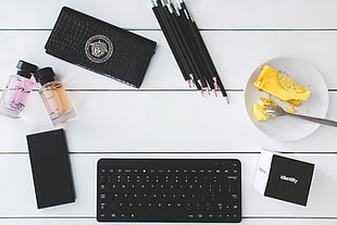 black portable keyboard with pencil, spray bottles, wallets, and white plate